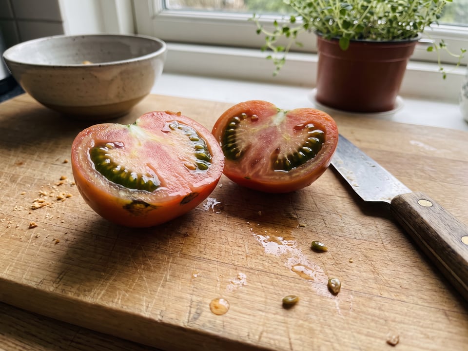 A ripe heirloom tomato cut across the middle showing seed cavities full of jelly