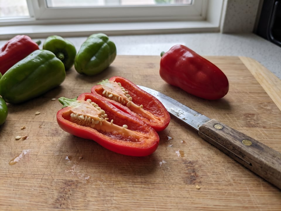 A Cajun Belle pepper cut open lengthwise beside a whole pod, showing the wall and seed cavity