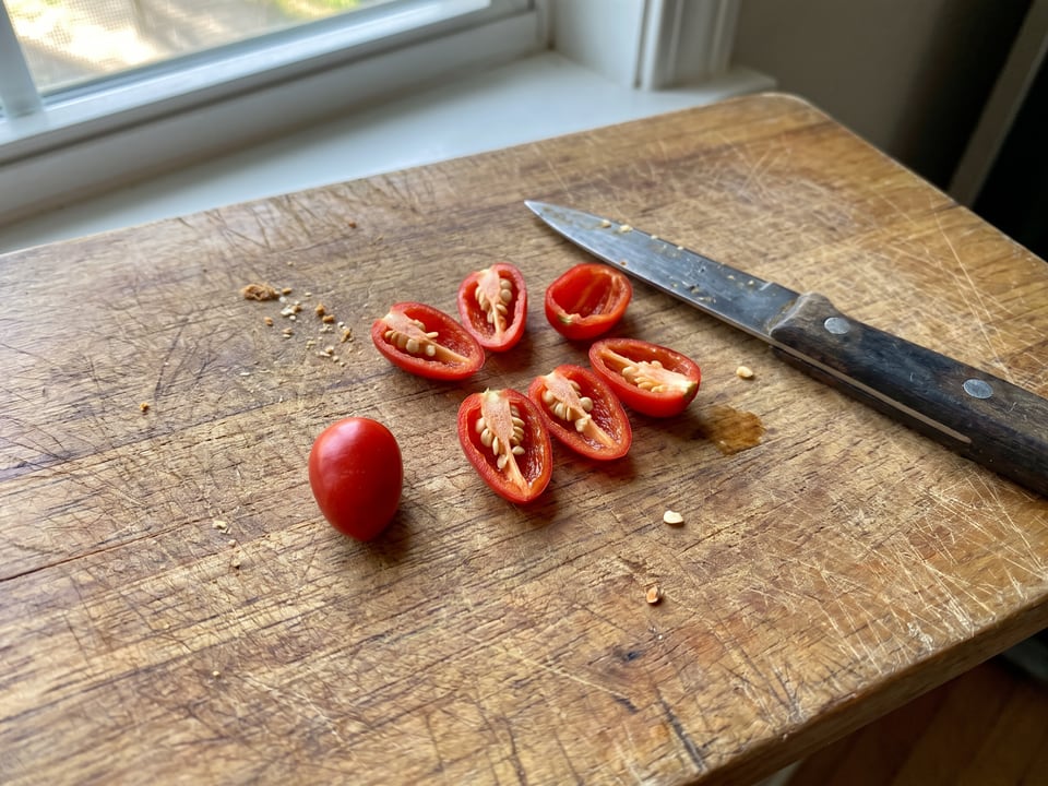 A Chiltepin pepper cut open lengthwise beside a whole pod, showing the wall and seed cavity