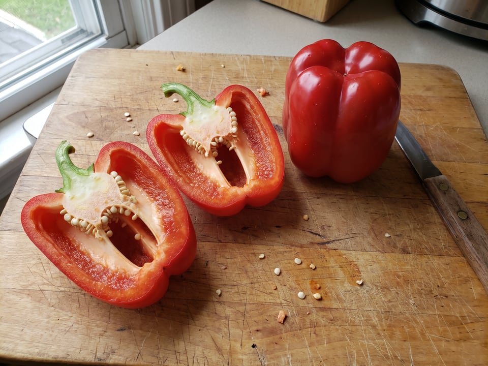 A Chinese Giant pepper cut open lengthwise beside a whole pod, showing the wall and seed cavity