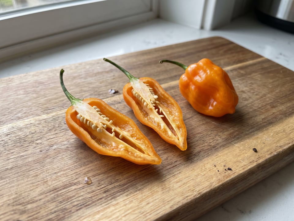A Habanada pepper cut open lengthwise beside a whole pod, showing the wall and seed cavity